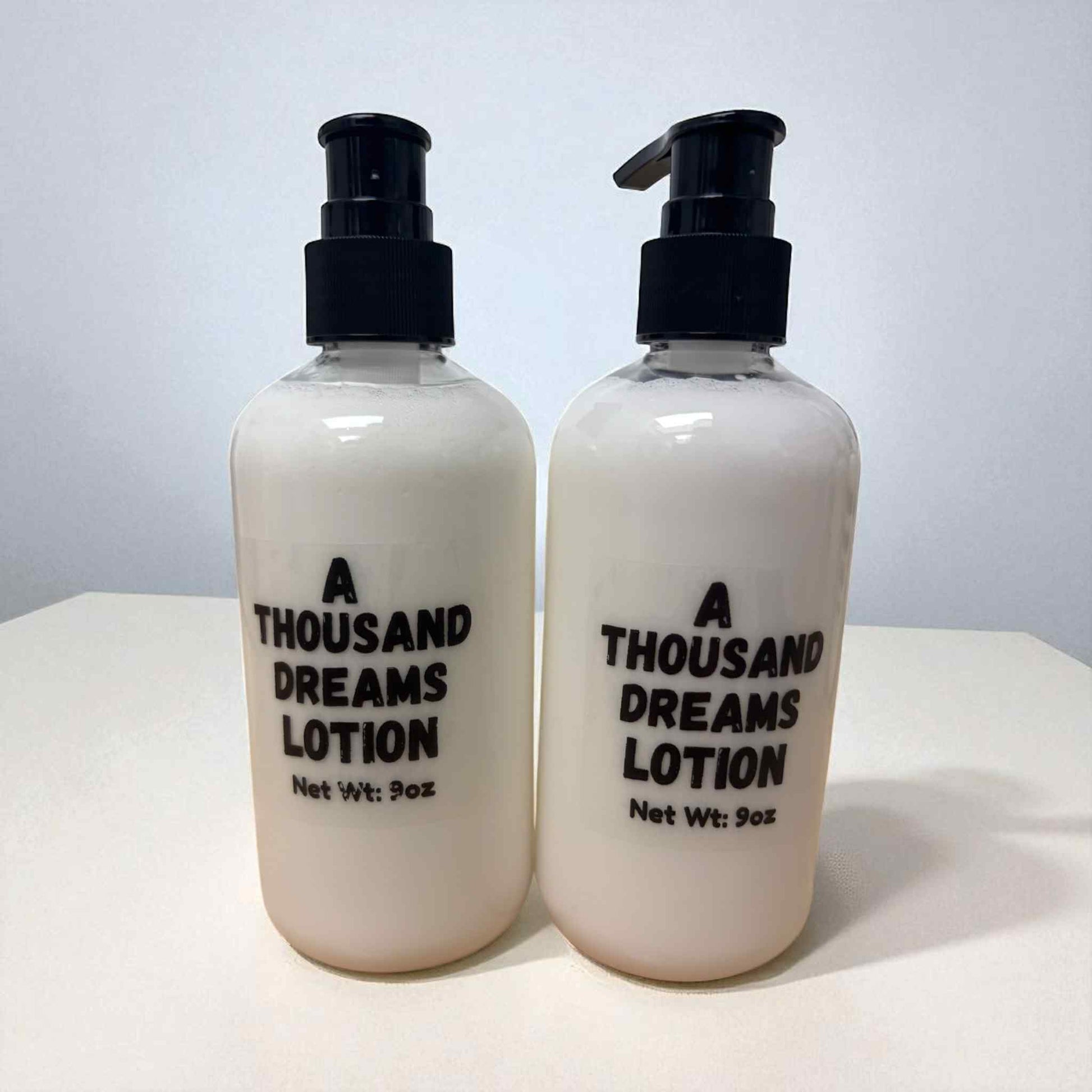 Two bottles of 'A Thousand Dreams Lotion' on a white surface with a light gray background.
