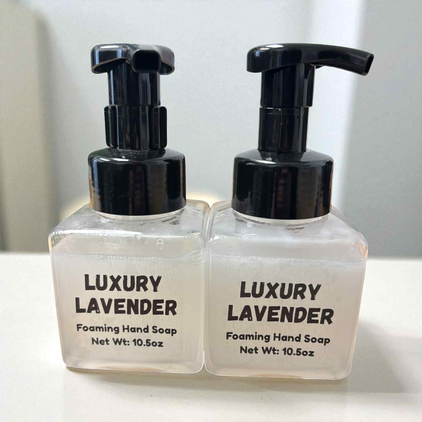 Two bottles of Luxury Lavender foaming hand soap with black pumps on a white background.