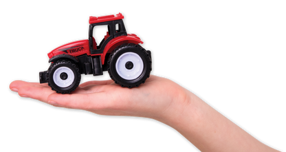 Small red toy tractor held in a hand against a white background