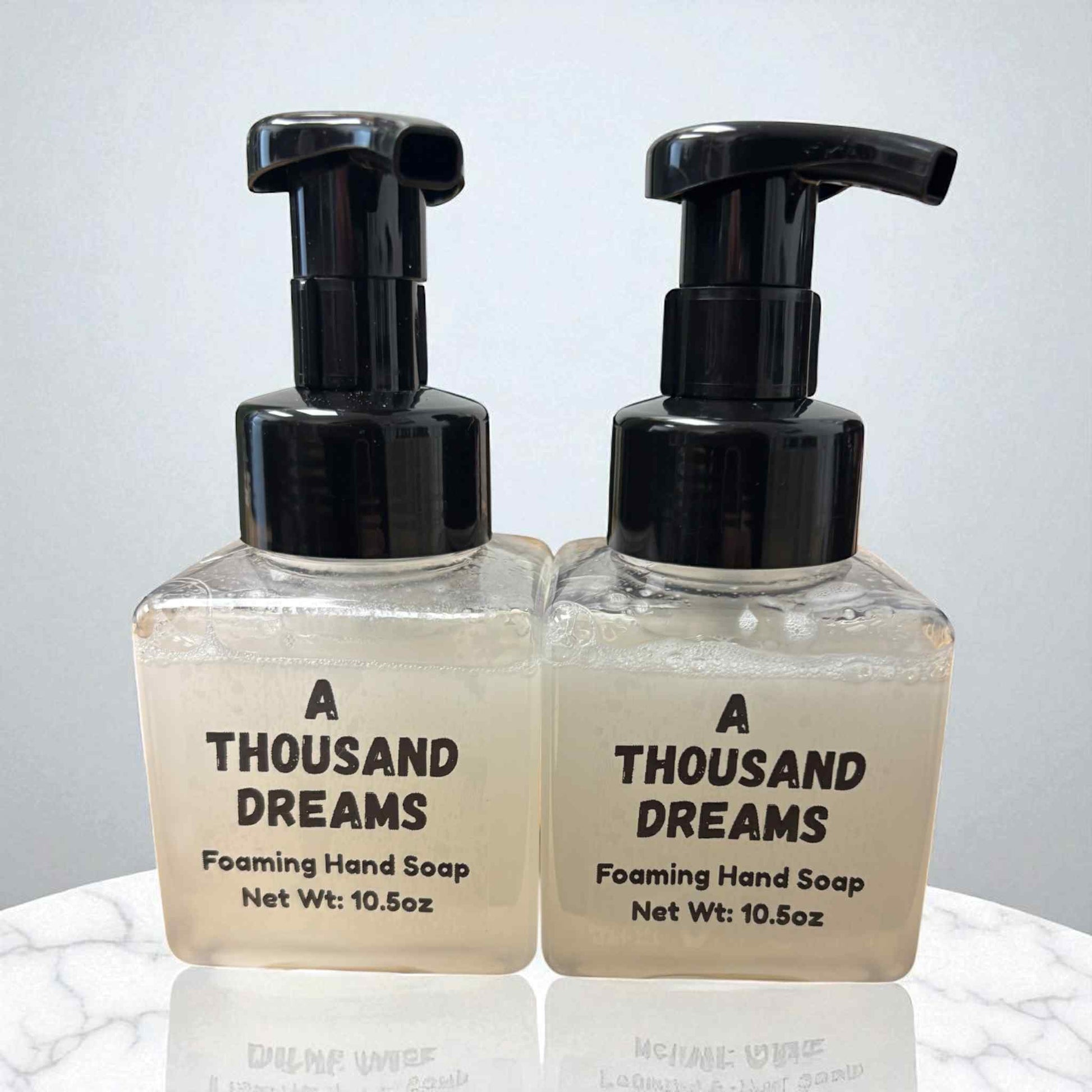 Two bottles of 'A Thousand Dreams' foaming hand soap on a light background