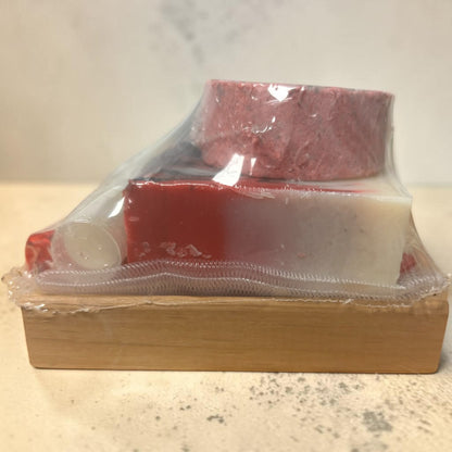 Red meat in clear plastic packaging on a wooden block with a white background