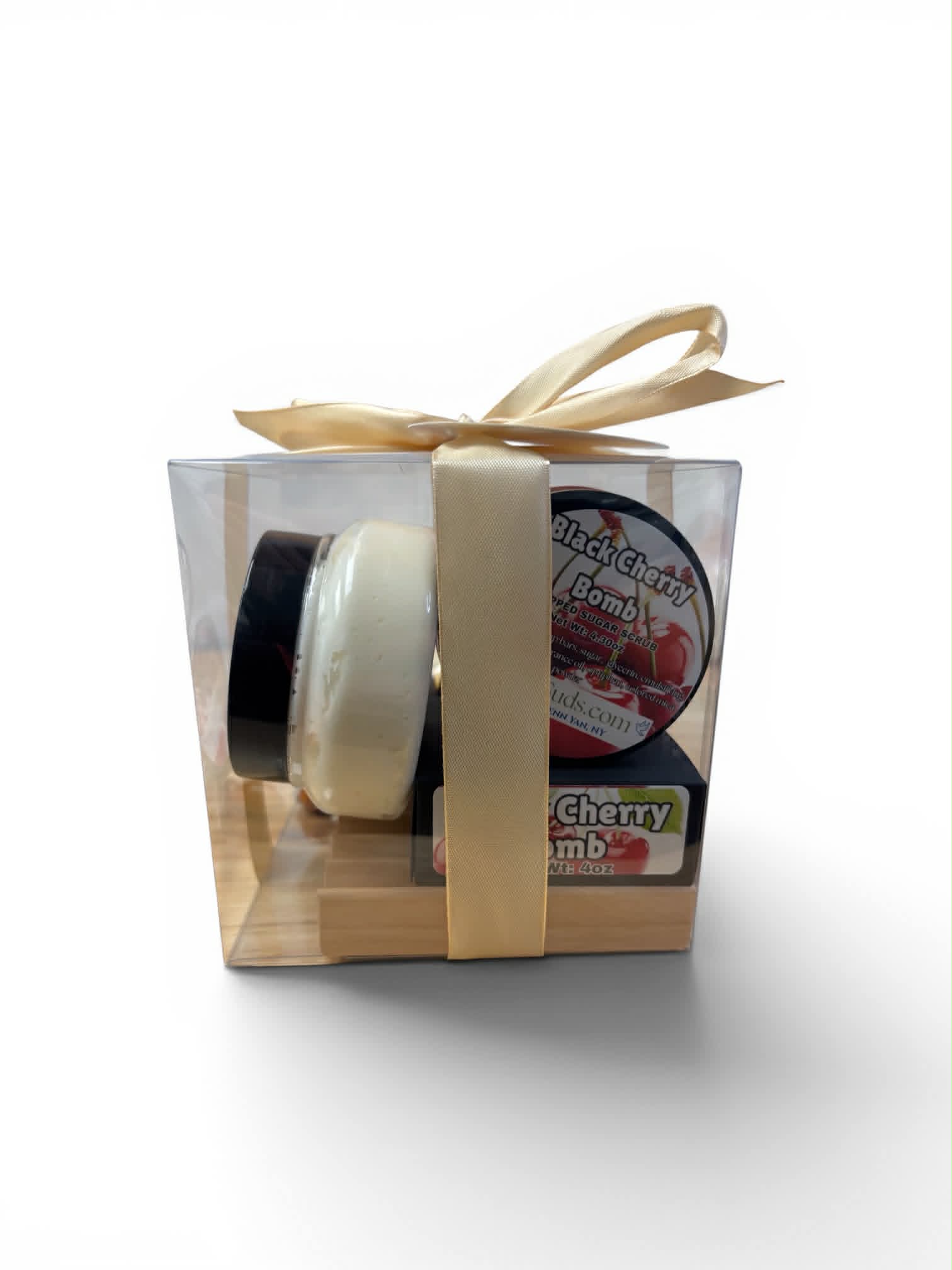 Two small cylindrical products in a clear gift box with a gold ribbon on a white background.