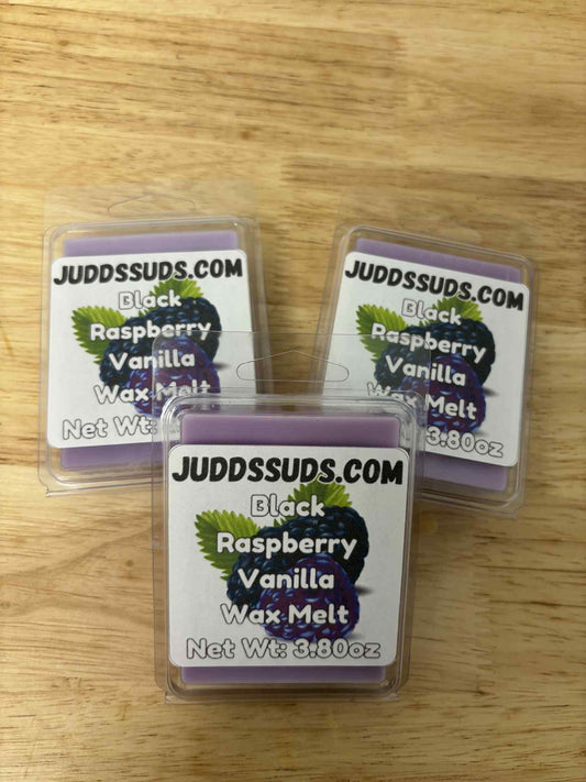Three packages of Judds Suds Black Raspberry Vanilla wax melts on a wooden surface.