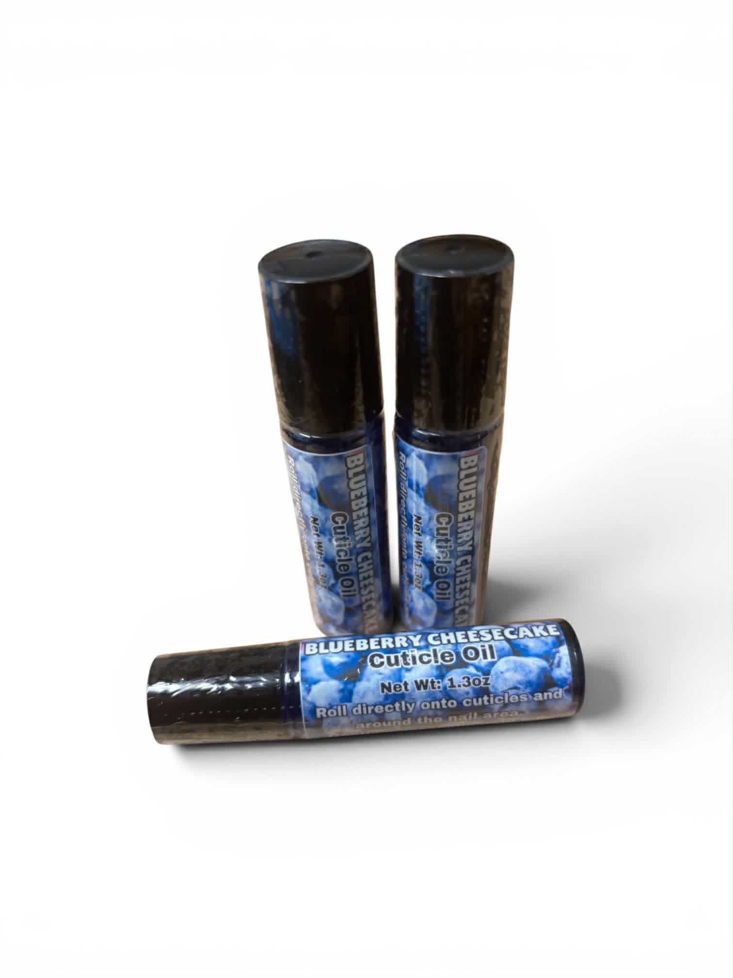 Three bottles of Blueberry Cheesecake cuticle oil on a white background
