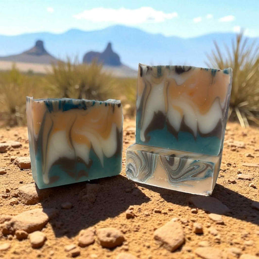 Two marbled soap bars on a desert landscape with mountains in the background