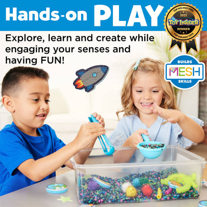 Alien sensory bin, contains space rocks, astronaut toy, squishy alien, foam planets, sparkly pom poms, tongs, spirals, glow in the dark stars, and scoop.