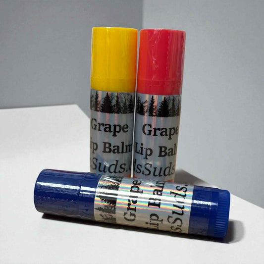 Three lip balm sticks with colorful caps on a gray background