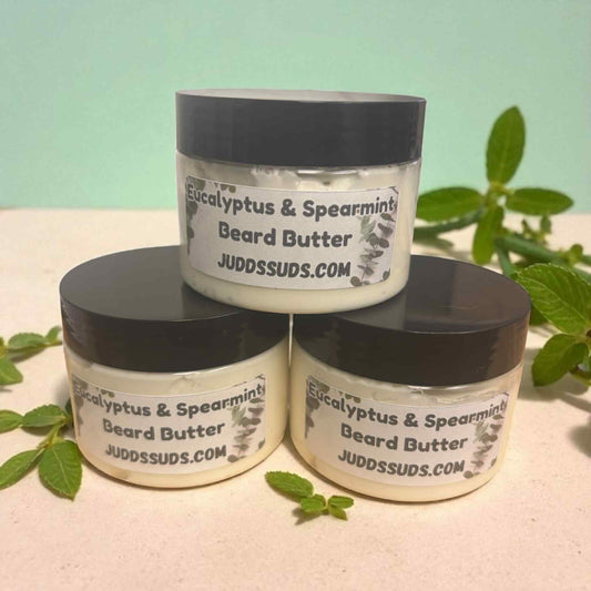 Three jars of Eucalyptus & Spearmint Beard Butter by Judds Suds on a light surface with greenery.