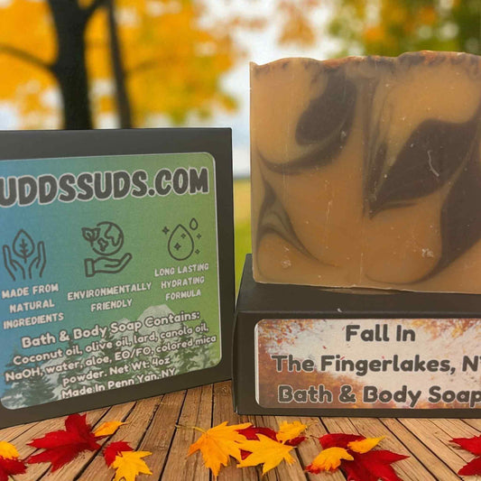 Bath and body soap with a leaf design and a sign for Udder Suds on a wooden surface with autumn leaves.