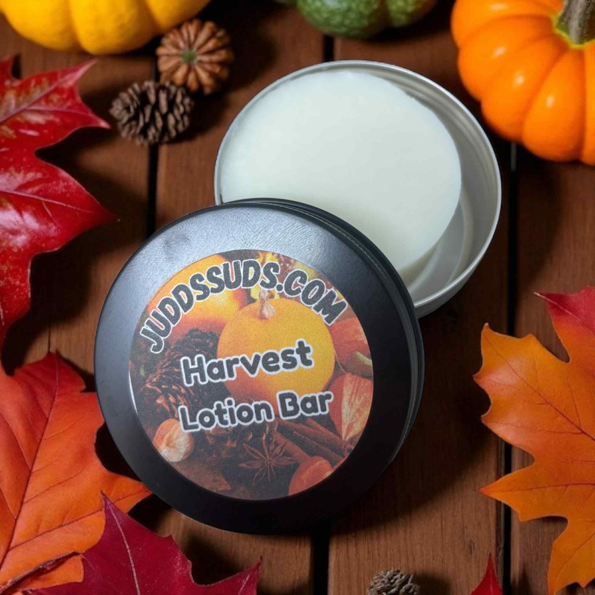 Harvest-themed lotion bar with a decorative label on a wooden surface with fall leaves and pumpkins.