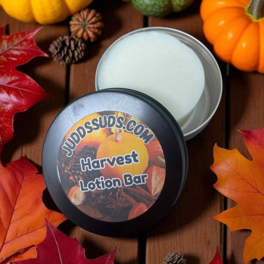 Harvest-themed lotion bar with a decorative label on a wooden surface with fall leaves and pumpkins.
