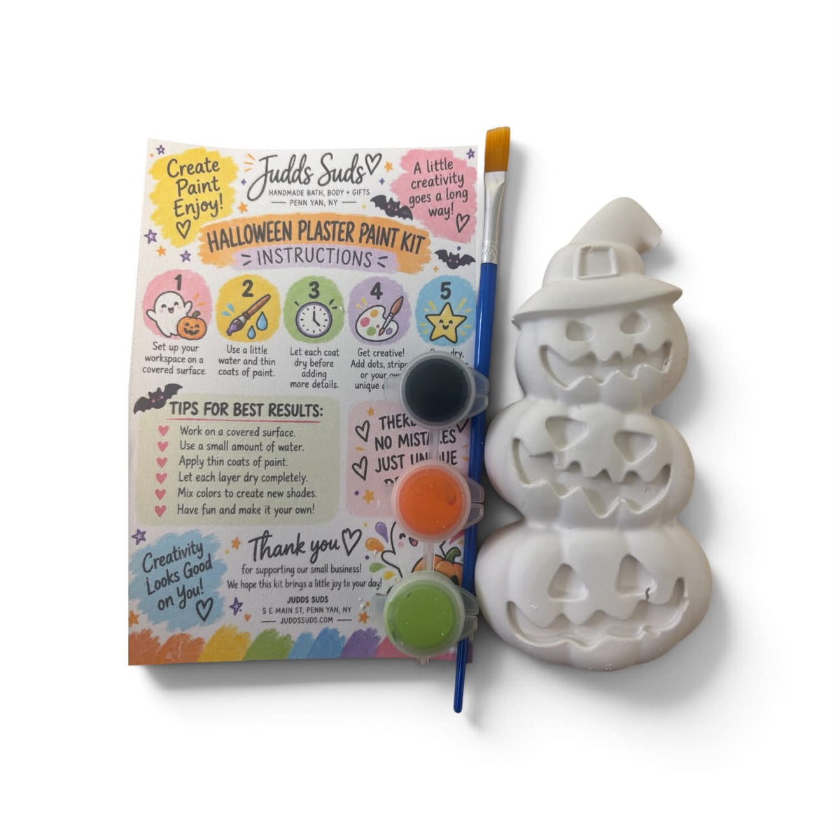 Halloween Plaster Paint Kit by Fjells Suds, featuring a white plaster pumpkin mold, a paintbrush, a printed instruction booklet, and three small paint pots on a white background.