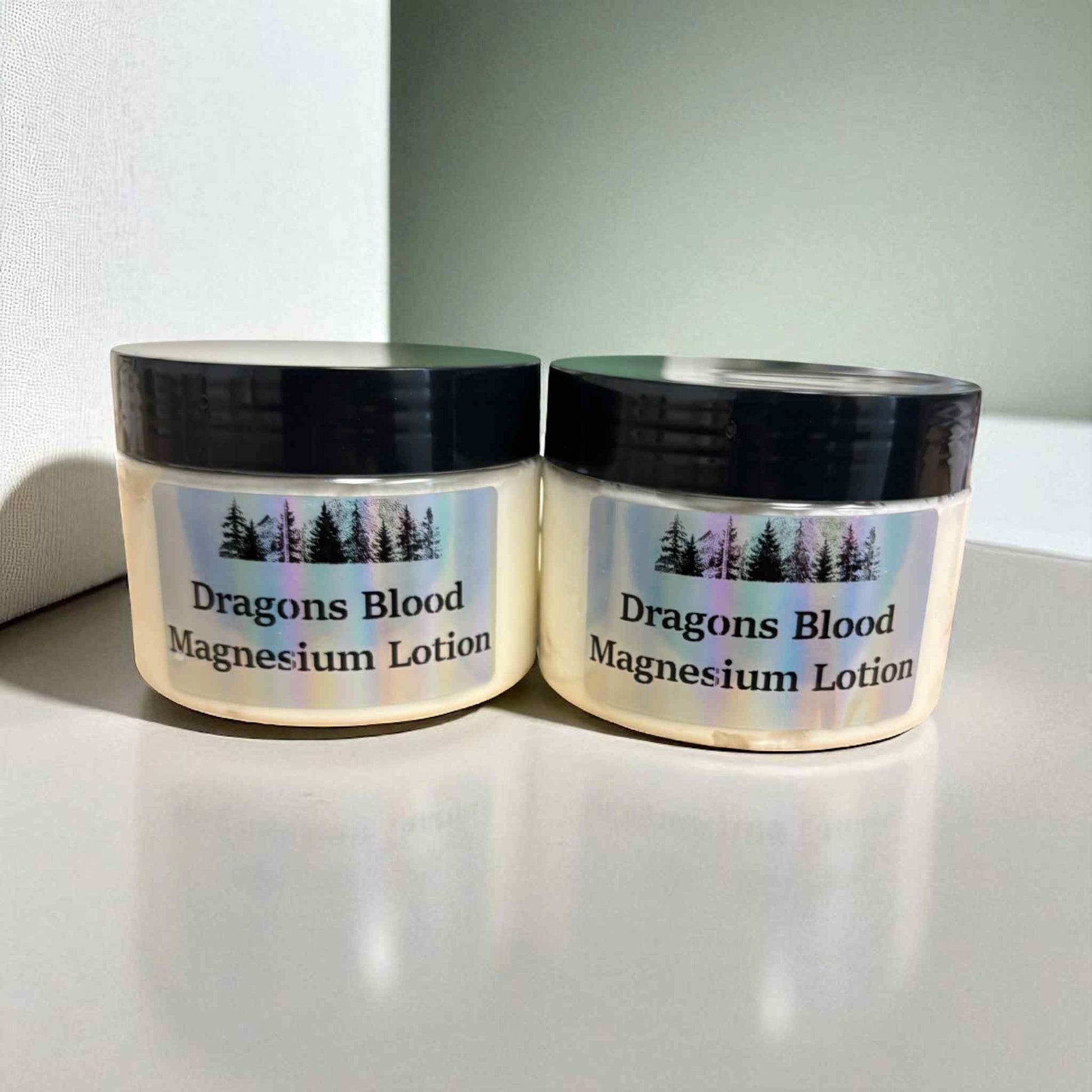 Two jars of Dragons Blood Magnesium Lotion on a light surface with a white background