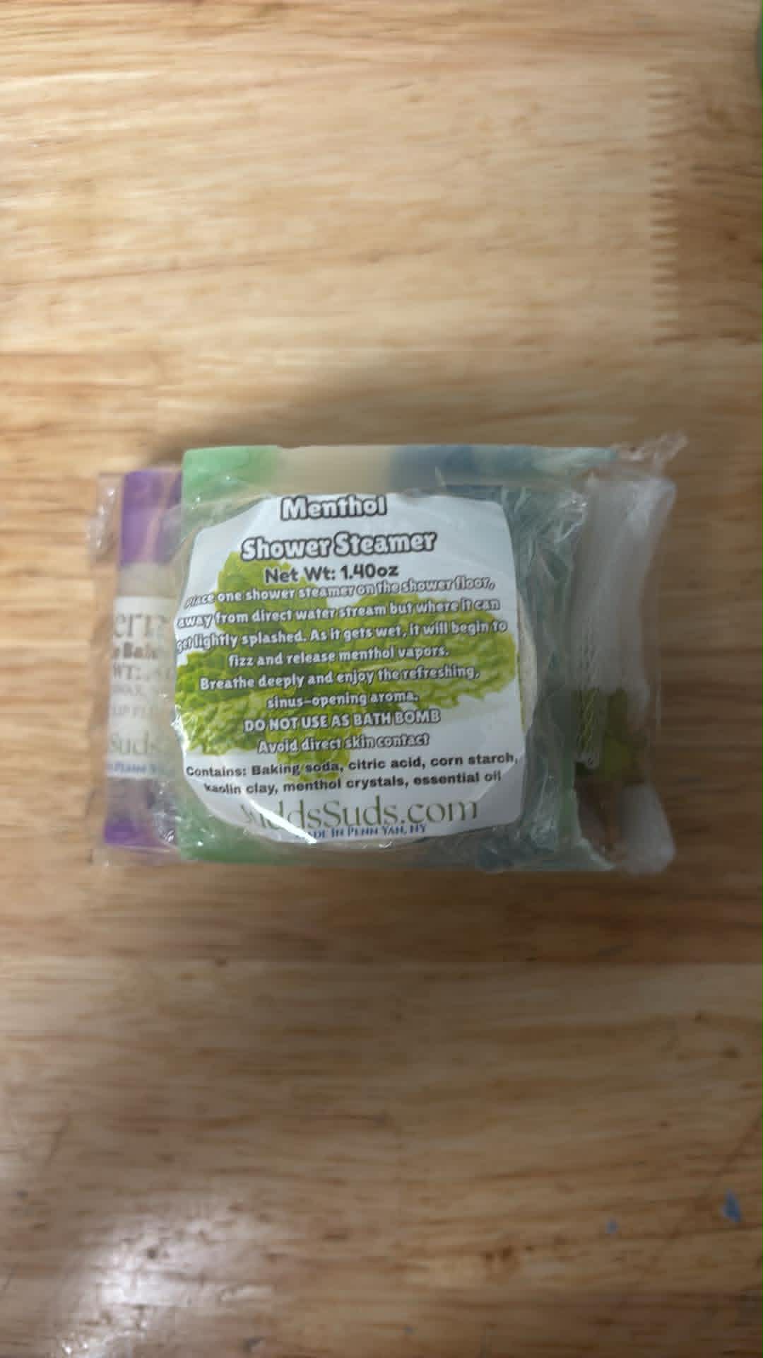 Menthol shower steamer packaging on a wooden surface