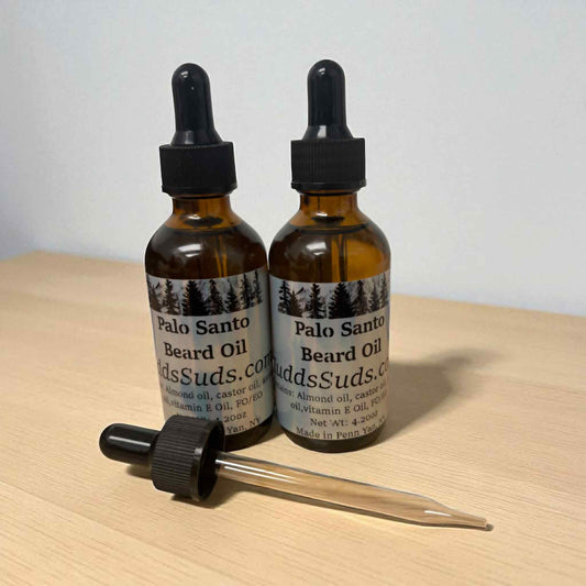 Two bottles of Palo Santo Beard Oil with droppers on a wooden surface.