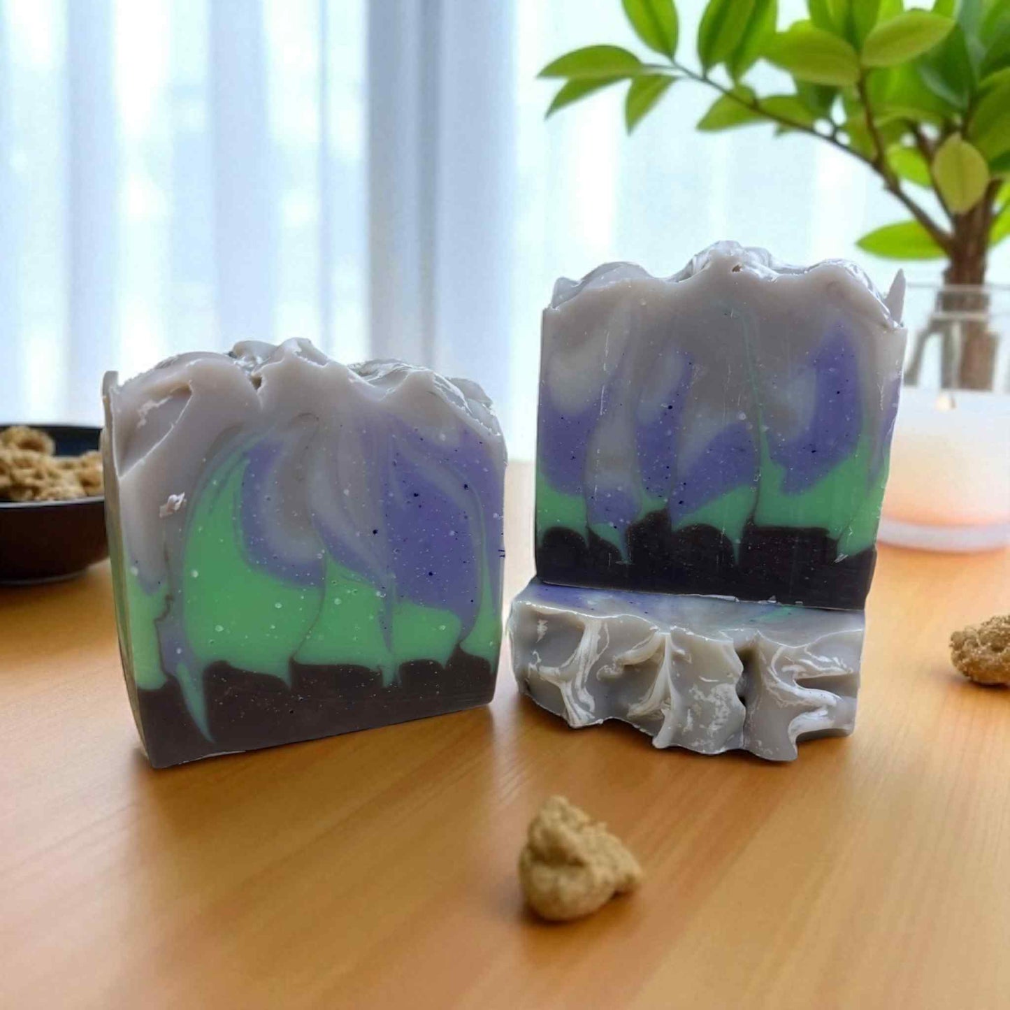 Two handmade soap bars with colorful swirls on a wooden surface.