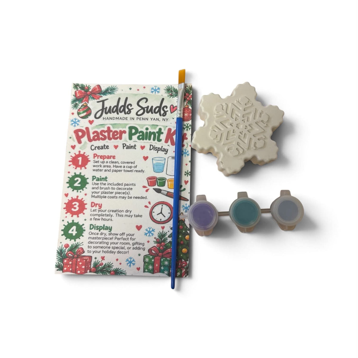 Judd's Suds Plaster Paint Kit with a snowflake mold, paint palette, paintbrush, and printed instruction booklet on a white background.